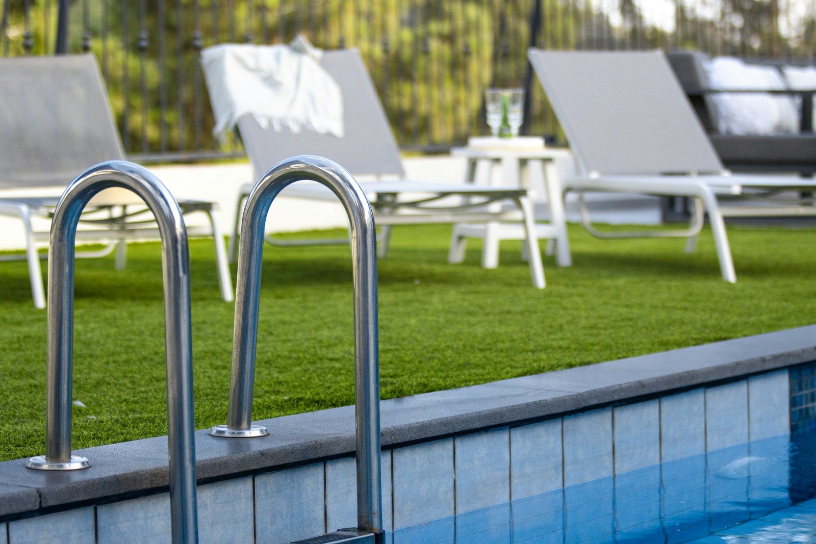 Swimming pool ladder with lounge chairs on grass
